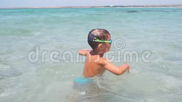 快乐的小男孩在海浪上跳跃享受暑假视频的预览图