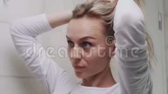 一位年轻女子把头发扎成松紧带看着镜子视频的预览图