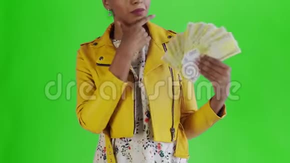 体贴成功的非洲裔美国妇女与金钱爱好者在绿色背景工作室黄色夹克视频的预览图