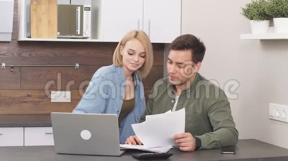 白种人年轻夫妇在桌旁阅读和分析账单视频的预览图
