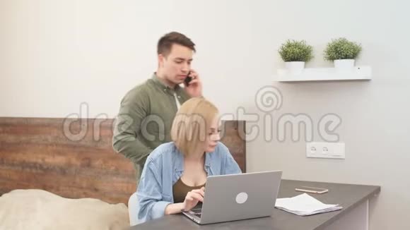 女人在笔记本电脑上工作而他的丈夫在打电话视频的预览图