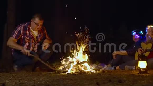 在森林远足营地生火的游客在篝火旁放松的旅行家庭少女玩耍视频的预览图