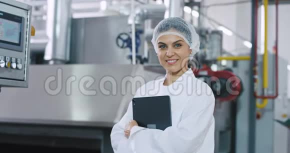 画像上微笑着的大女工程师非常迷人手里拿着电子平板电脑站在工业旁边视频的预览图