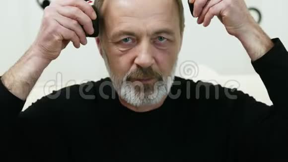 现代中年男人的肖像戴上无线耳机享受音乐留着灰色胡须视频的预览图