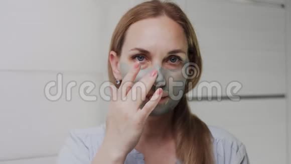 特写成年女性脸上戴着黏土面具看着镜头视频的预览图