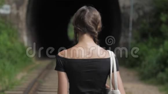 穿敞肩T恤的女孩沿着旧棕色铁路行走视频的预览图