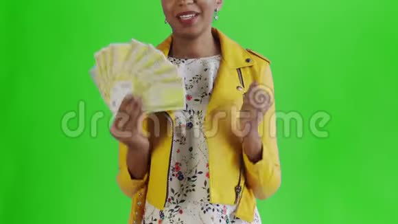 心满意足兴奋的非洲裔美国妇女在绿底黄夹克上卖钱说好视频的预览图