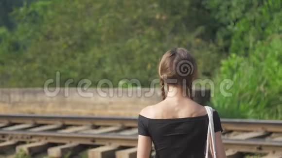 黑衣女孩在大自然中慢步走向铁路视频的预览图