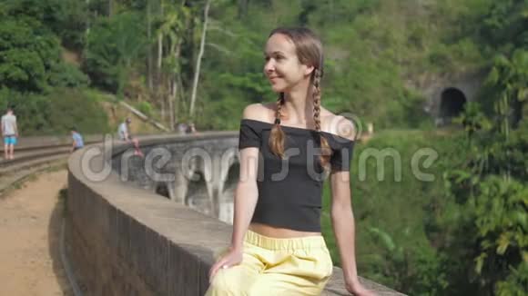 女人坐在历史桥上与狂野的风景相映成趣视频的预览图