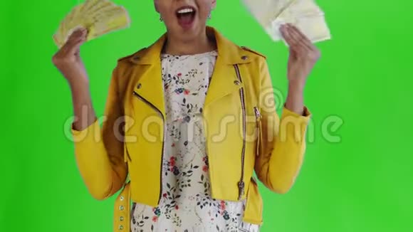 满意高兴兴奋非裔美国妇女展示钱说我的上帝在绿色背景黄色夹克视频的预览图