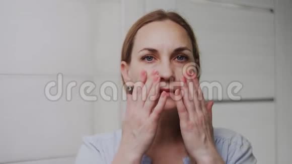 一个沮丧的成年女人看着浴室里的摄像机视频的预览图