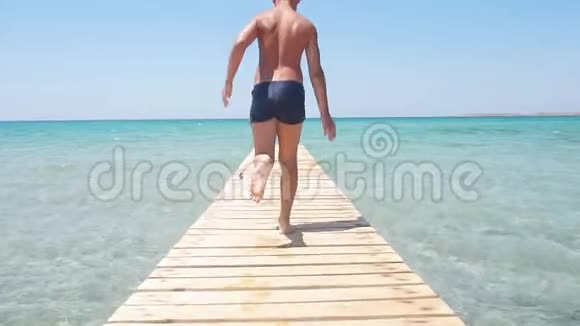 快乐的男孩在海滩上沿着海滨跑步视频的预览图