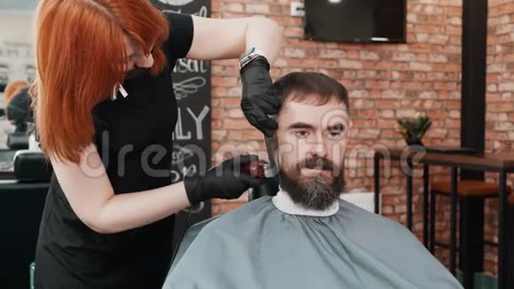 理发师用电动剃须刀给男性沙龙里的时髦男士剪胡子胡子男人用剃须刀刮胡子视频的预览图