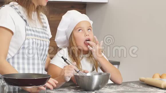 年轻的厨师们正在准备蛋糕小女孩品尝面团视频的预览图