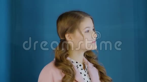 在深蓝色背景下一个微笑着的快乐女孩少女的肖像一脸可爱的卷发女生视频的预览图