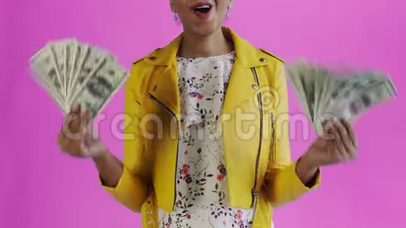 满意快乐兴奋的非洲裔美国妇女在粉红色背景上展示金钱和说上帝啊的肖像视频的预览图