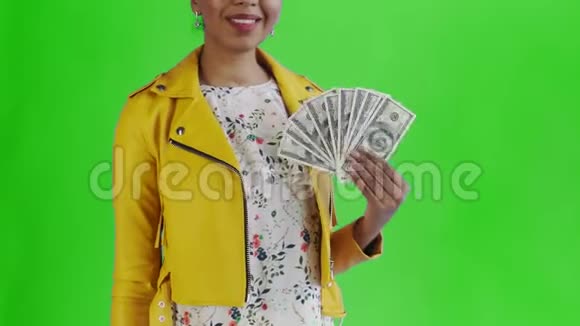 美国黑人妇女在工作室的绿色背景上有钱粉丝的肖像黄色夹克视频的预览图