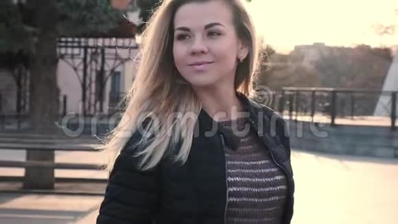 日出时分一位金发碧眼的年轻美女在城市的人行道上悠闲散步视频的预览图
