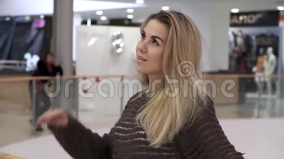 年轻漂亮女人的肖像金发长发等待站在室内购物中心在一个城市视频的预览图
