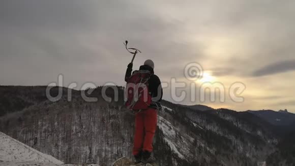 一个年轻的男性登山者站在山顶手里拿着一把冰斧的轮廓视频的预览图