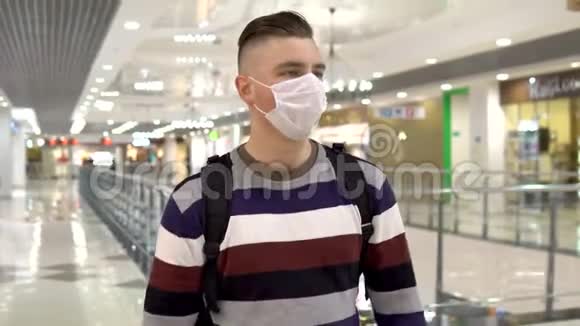 一个戴着医用口罩的年轻人在购物中心散步那人在咳嗽蒙面人保护自己不受视频的预览图