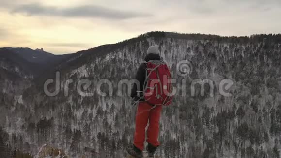 日落时一个孤独的年轻男性徒步旅行者站在山顶上视频的预览图