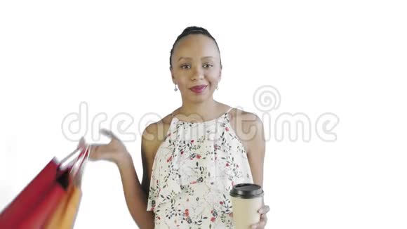 美国黑人妇女带着购物袋的肖像正在工作室的白色背景上喝咖啡J白色连衣裙视频的预览图
