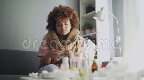 生病的非洲裔美国女孩躺在沙发上用水吃药视频的预览图