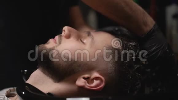 现代沙龙男理发师为顾客洗头视频的预览图