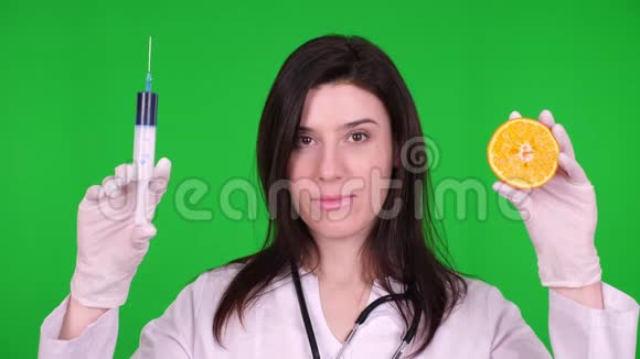 年轻的女医生营养学家穿着白色的医疗制服带听诊器一人拿着半个橘子视频的预览图