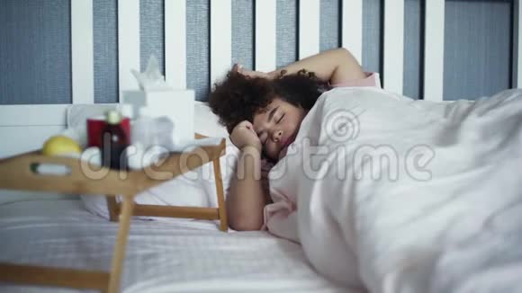 生病的年轻非裔美国女孩在疾病中睡觉躺在床上视频的预览图
