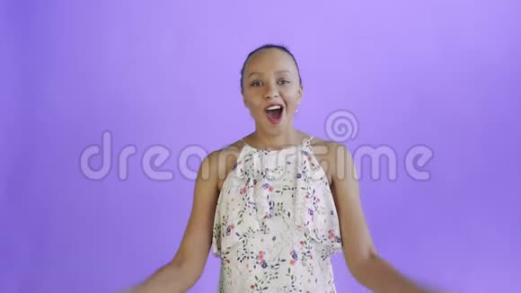满意的高兴兴奋的非裔美国妇女显示金钱和说我的上帝在紫色背景白色连衣裙视频的预览图