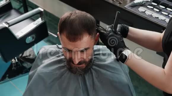 理发师用剪刀和梳子剪雄性头发有胡子的人拿着剪刀理发视频的预览图