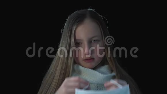 生病的女孩戴着医疗面罩一个生病的女孩在黑色背景的医疗面具上的肖像咳嗽的概念视频的预览图