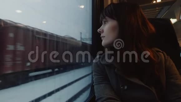 年轻体贴的微笑迷人的白人妇女的画像看着窗外的火车在窗口座位慢动作视频的预览图