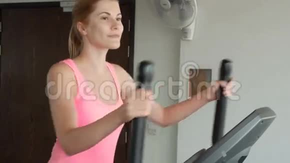 漂亮的健身运动积极的年轻女子在健身房锻炼椭圆健身教练视频的预览图