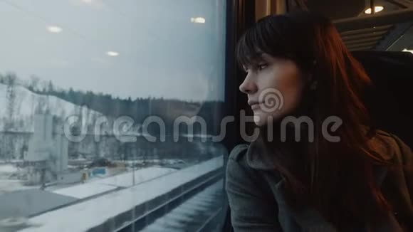 体贴的年轻迷人的欧洲女人的肖像从移动的冬季火车在窗口座位慢动作视频的预览图