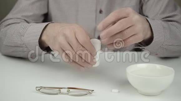 穿灰色衬衫的老人用颤抖的双手服用白色药丸视频的预览图
