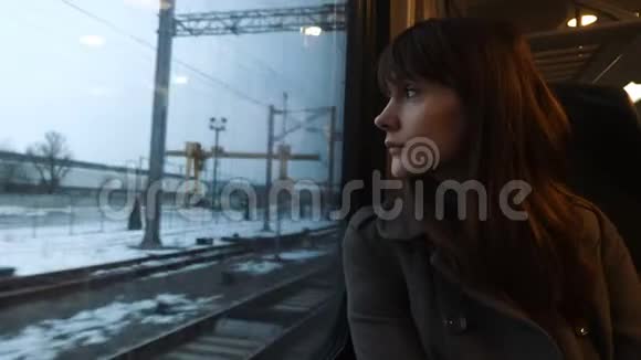 年轻冷静体贴美丽的白种人女人从火车车窗外望向乘客座位慢动作的肖像视频的预览图