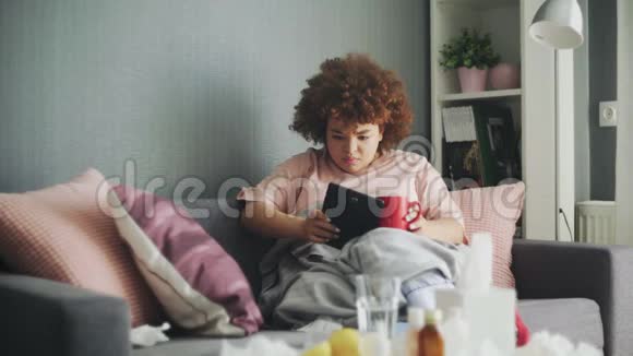 生病的非洲裔美国年轻女孩在家使用平板电脑视频的预览图