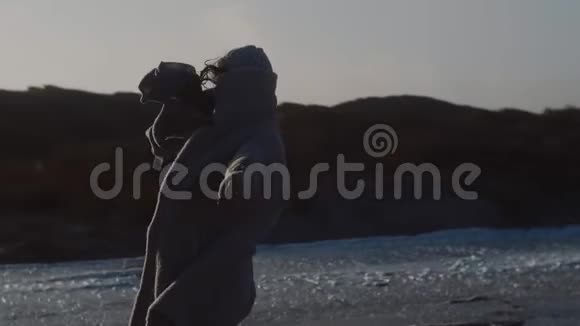 美丽的快乐的旅游妇女在寒冷的阳光下在寒冷的冬天在海岸缓慢的运动中依靠着非常强的风视频的预览图