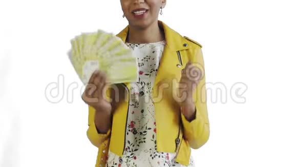 满意高兴兴奋非洲裔美国妇女展示钱说YEAH在白色背景黄色夹克视频的预览图