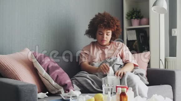 生病的非裔美国女孩在家里沙发上患流感病毒她用湿巾打喷嚏视频的预览图