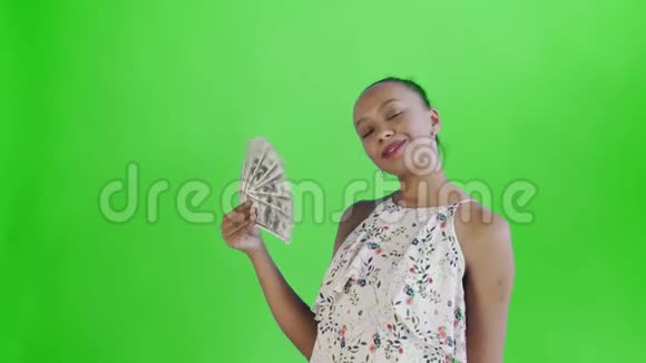 美国黑人妇女在工作室的绿色背景上有钱迷带花的白色裙子视频的预览图