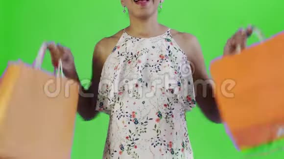 特写镜头中一位非洲裔美国妇女正在摄影棚里拿着绿色背景的购物袋跳舞幸福女人抱视频的预览图