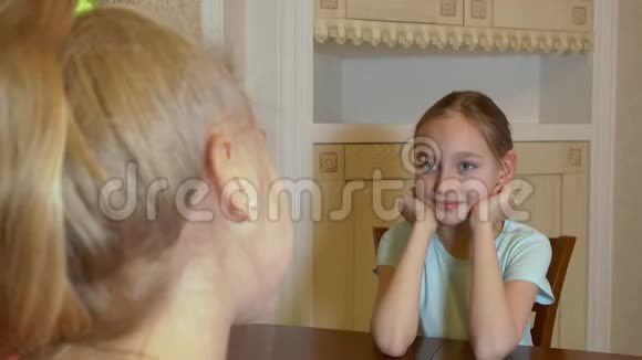 快乐的小女孩坐在餐桌旁在家里笑视频的预览图