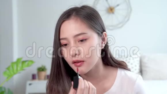 漂亮的亚洲女人用刷子把口红涂在嘴唇上来弥补自己视频的预览图