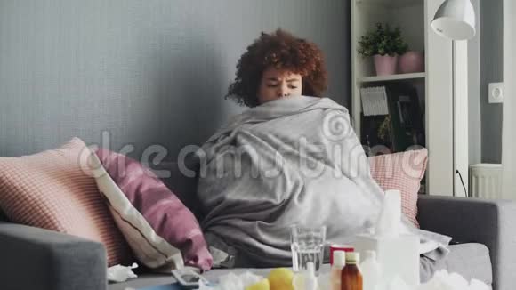 身上裹着灰色格子的非洲裔美国年轻女孩在家里感到寒冷生病的女孩发烧感冒视频的预览图