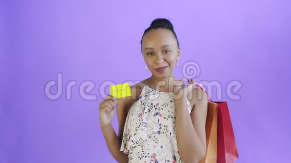 非裔美国妇女手里拿着信用卡和包裹紫色猎犬带花的白色裙子视频的预览图