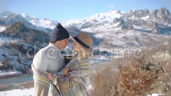 这对年轻夫妇在美丽的雪山背景下拥抱亲吻视频的预览图